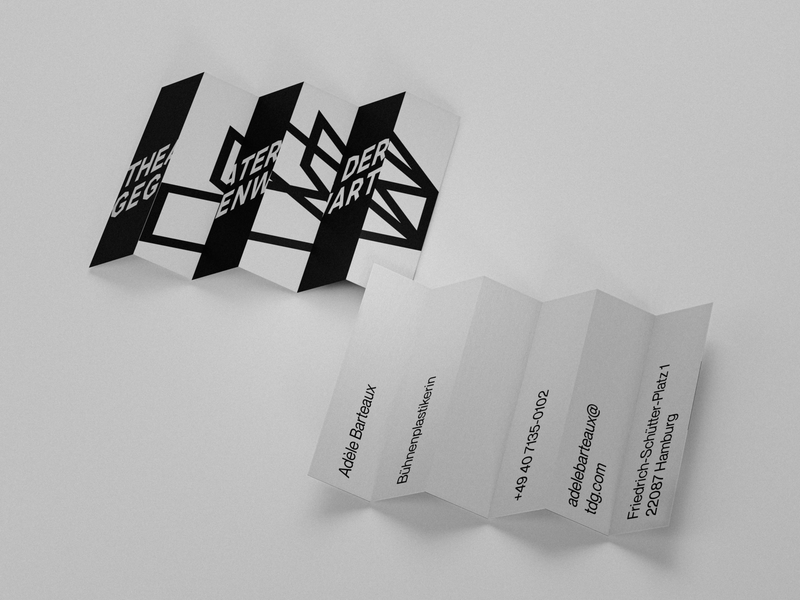 Business cards unfolded and spread out, revealing the anamorphic logo on the front and contact details on the white reverse